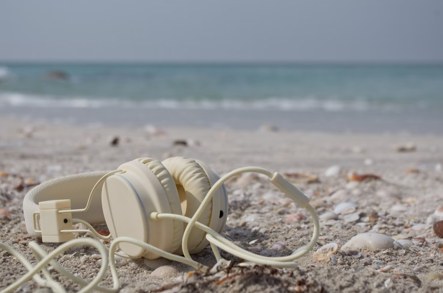 Auriculares blancos sobre la arena de la playa