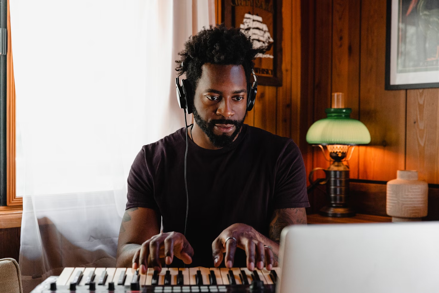 Músico escribiendo canciones con un teclado y un portátil