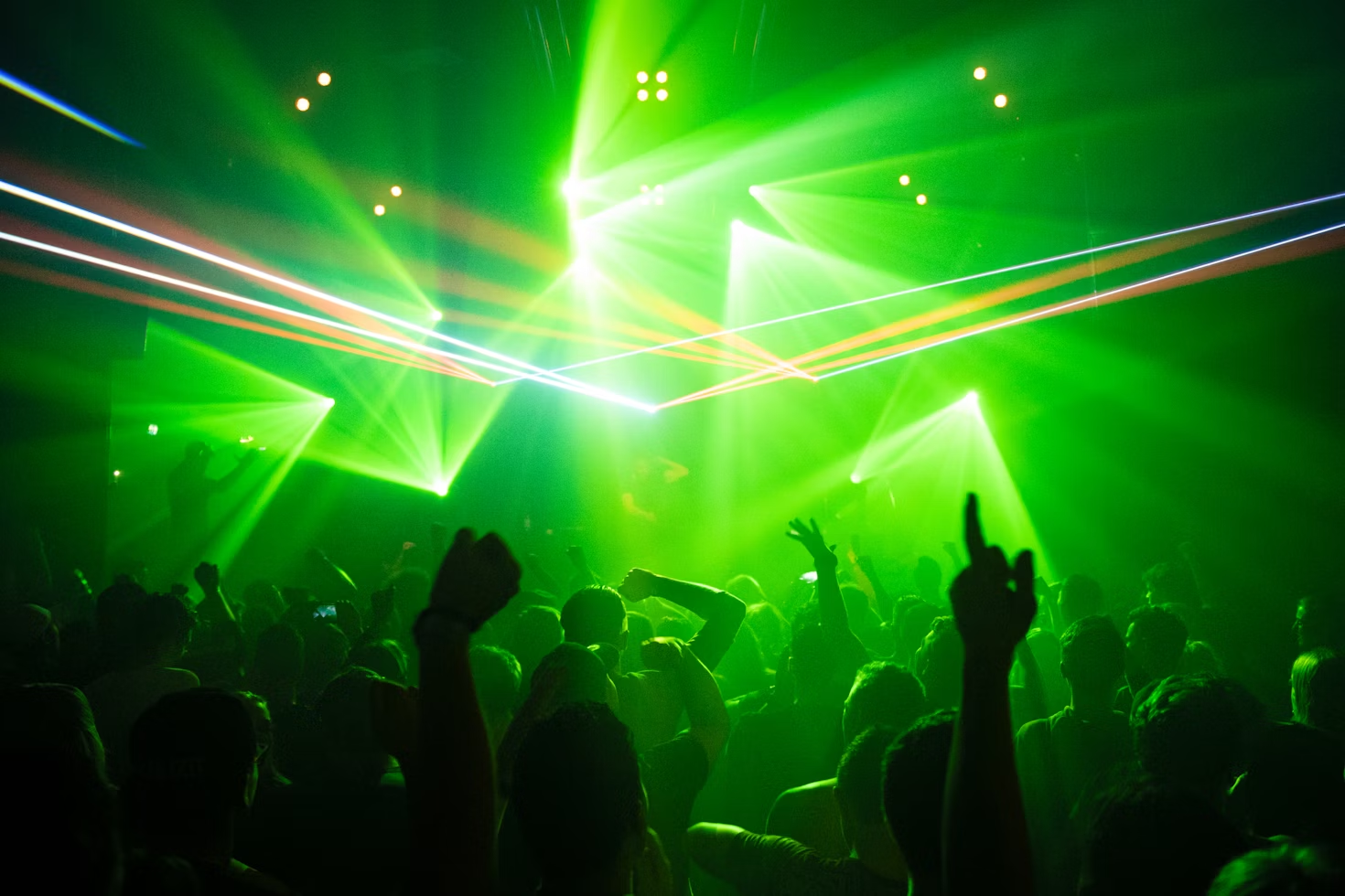 Gente bailando en una discoteca bajo luces verdes.