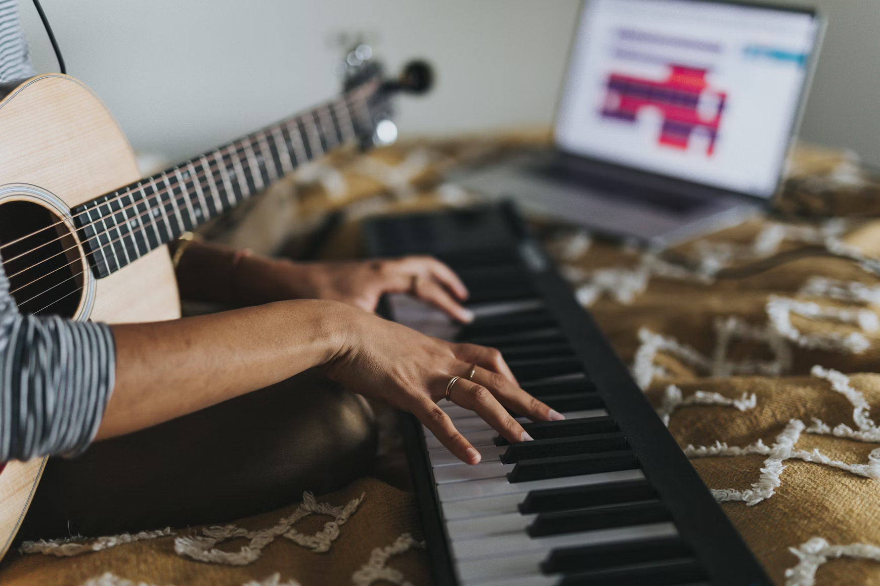 Músico tocando el piano con una guitarra en el regazo.