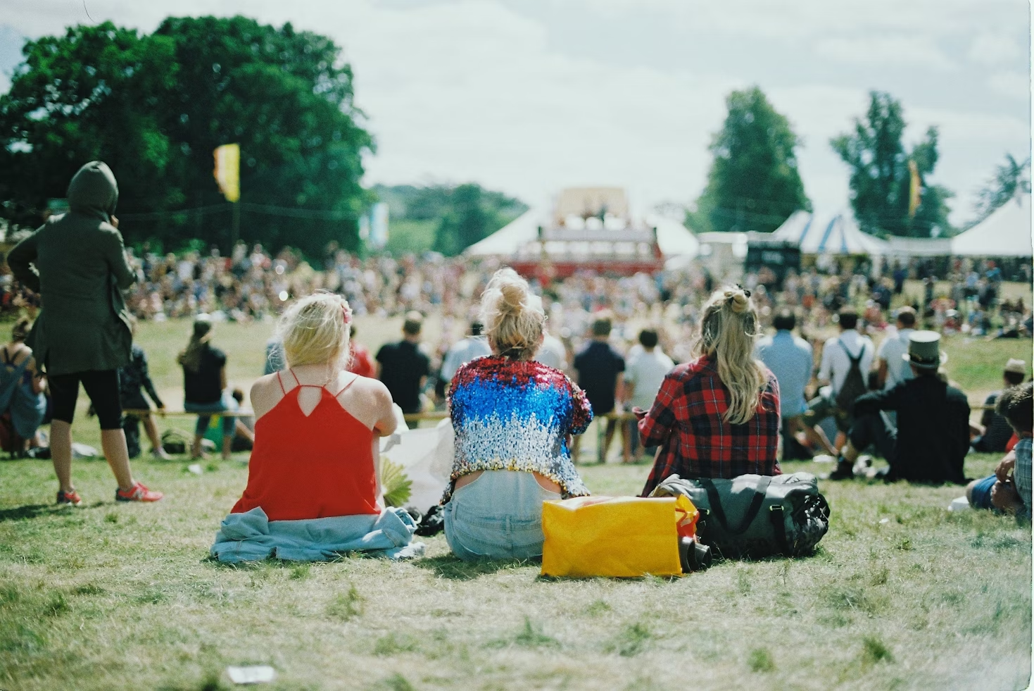 Público de un festival sentado en la hierba.