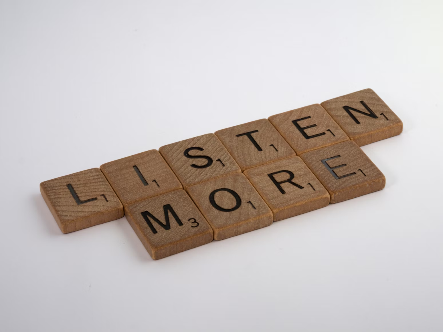 Fichas de madera agrupadas para decir 'listen more'.