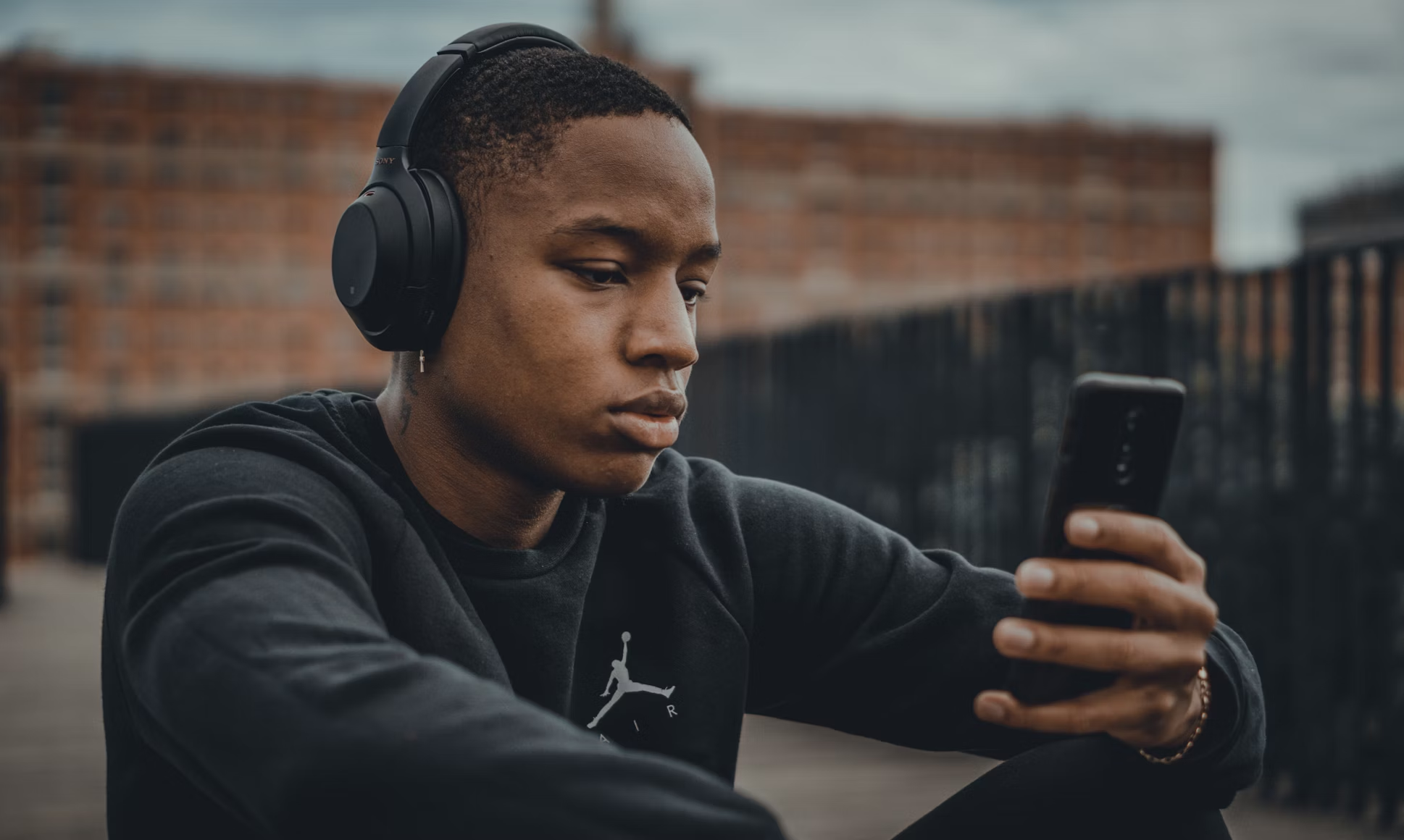 Joven escuchando música con auriculares en el móvil.