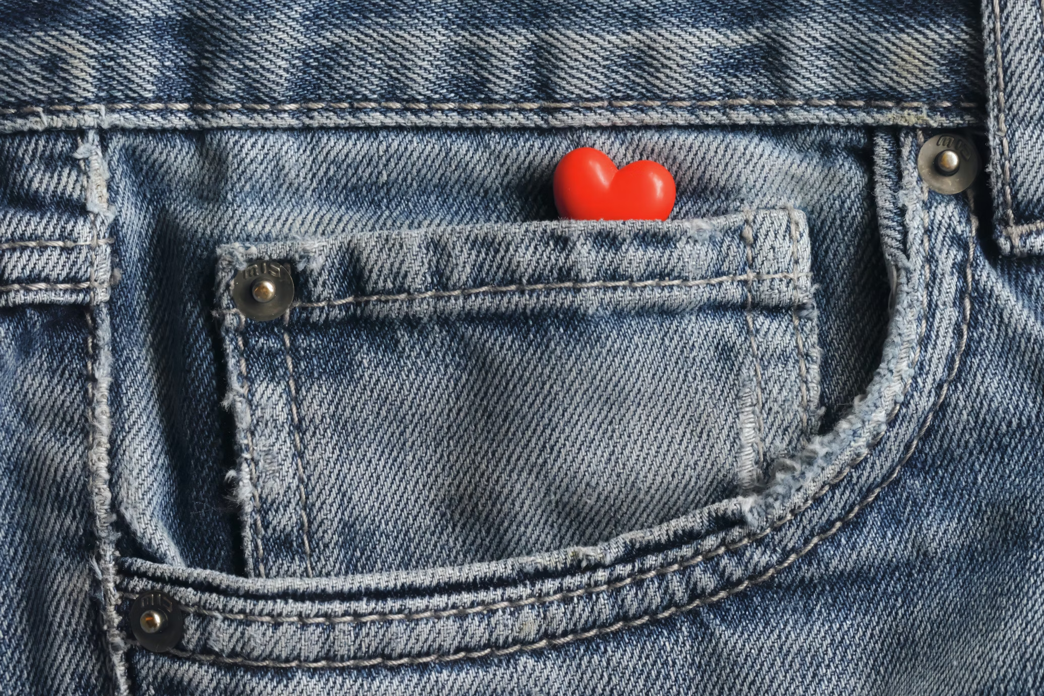 Un corazón rojo en el bolsillo de unos pantalones vaqueros.